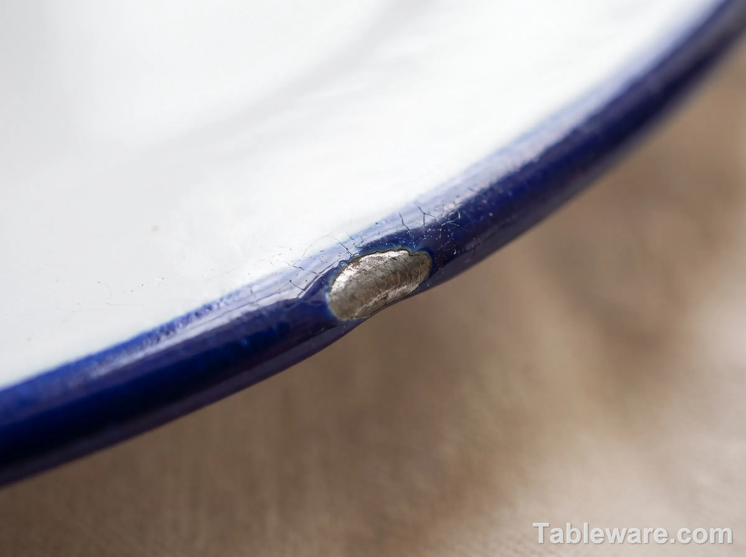 Close-up of a small chip in a cobalt blue enamel rim exposing grey steel underneath